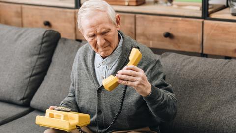 Ein alter Mann schaut verwirrt auf ein Telefon
