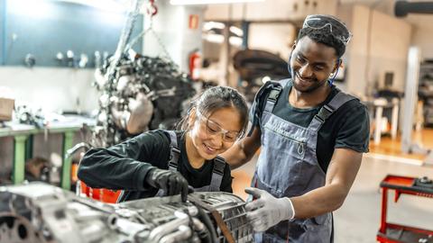 Mann und Frau bei der Arbeit an einem Automotor