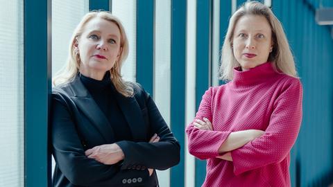 Das Bild zeigt die Intendantinnen des Staatstheaters Wiesbaden Beate Heine und Dorothea Hartmann in einem Flur. Beide haben die Arme verschränkt.