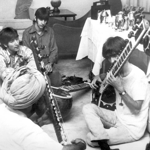 George Harrison nimmt Sitar-Unterricht in Neu Delhi, während Paul McCartney, John Lennon und Ringo Starr zuschauen.