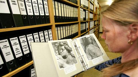 Eine Mitarbeiterin des Bildarchivs Foto Marburg blättert in einem Ordner mit Kunstaufnahmen