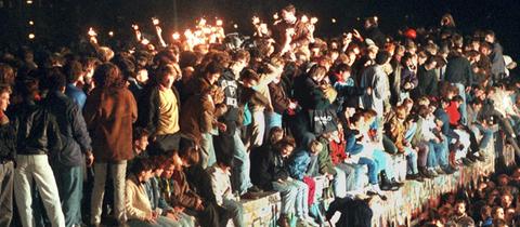  11.11.1989, Berlin: Jubelnde Menschen sitzen mit Wunderkerzen auf der Berliner Mauer am 11.11.1989. (zu "Themenpaket 30 Jahre Mauerfall am 9. November 1989") 