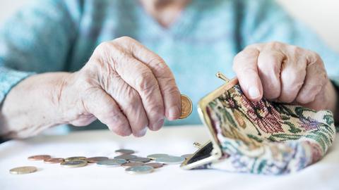 alte Frau sucht Münzen im Portemonnaie