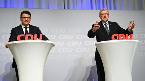 Zwei Männer in schwarzen Anzügen stehen vor Pulten mit einem Schriftzug CDU