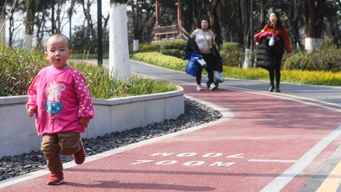 Ein Kleinkind geht auf einem neu asphaltierten Fußweg in der chinesischen Stadt Chongqing