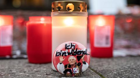 Teilnehmer einer Protestkundgebung haben Kerzen für die Opfer von sexuellem Missbrauch in der Kirche entzündet, an dem eine Sticker mit einem Bild vom emeritierten Papst Benedikt XVI. lehnt, auf dem handschriftlich "Ich bin wütend" zu lesen ist.
