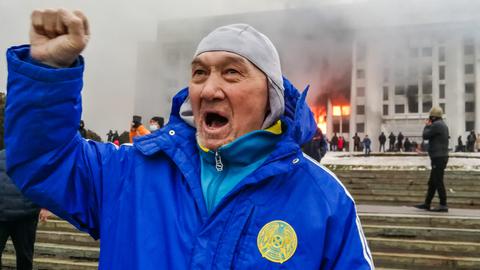 Ein Mann protestiert vor dem brennenden Rathaus in Amaty / Kasachstan. 