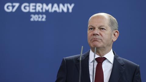 Scholz vor einer blauen Wand mit dem Schriftzug G7.