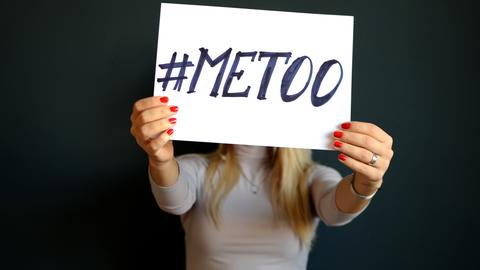 Eine Frau hält ein Schild mit der Aufschrift #metoo vor ihr Gesicht