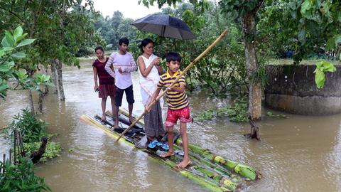 Menschen paddeln auf einem Floß nach einem heftigen Monsun.