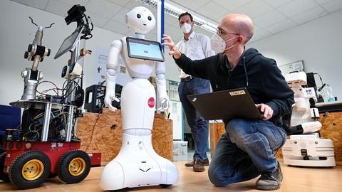Zwei Wissenschaftler arbeiten an einem menschenähnlichen Roboter.