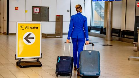 Eine Stewardess zieht ihren Rollkoffer durch das leere Flughafengebäude
