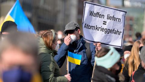 Ein Demonstrant trägt ein Schild mit der Aufschrift "Waffen liefern = Atomkrieggefahr".