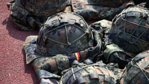 Ausrüstung für Soldaten, darunter ein Helm in Tarnfleck,  liegt auf dem Boden