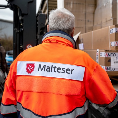 Ein Mitarbeiter des Malteser-Hilfsdiensts verlädt Hilfsgüter für die Ukraine.