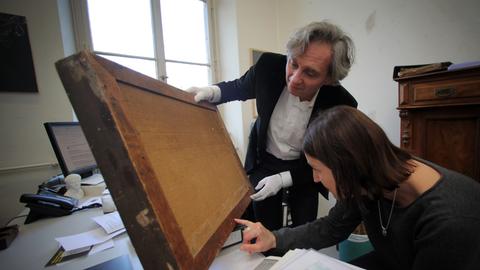 Peter Forster untersucht mit einer Kollegin im Museum Wiesbaden die Rückseite eines Bilds.