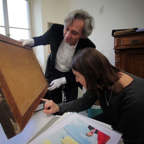 Peter Forster untersucht mit einer Kollegin im Museum Wiesbaden die Rückseite eines Bilds.