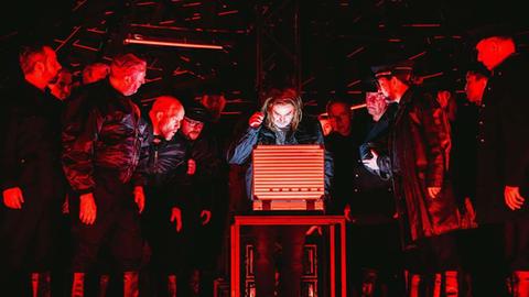 In roter Beleuchtung wird ein Koffer geöffnet: La Damnation de Faust am Staatstheater Kassel