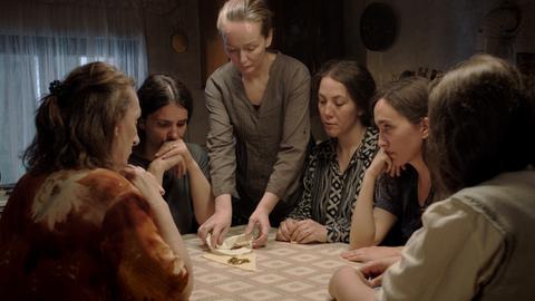 Mehrere Frauen sitzen an einem Tisch und schauen auf Patronenhülsen - Filmstill aus "Hive"