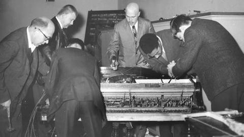 Fluxus 1962: Mehrere Männer nehmen ein Klavier auseinander 