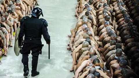 Ein Polizist überwacht zahlreiche Gefängnisinsassen.