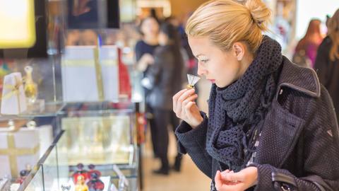 Eine Frau riecht an einer Parfümprobe in einem Kaufhaus.