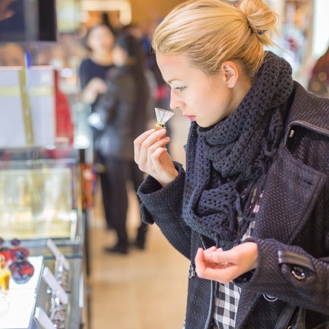 Eine Frau riecht an einer Parfümprobe in einem Kaufhaus.