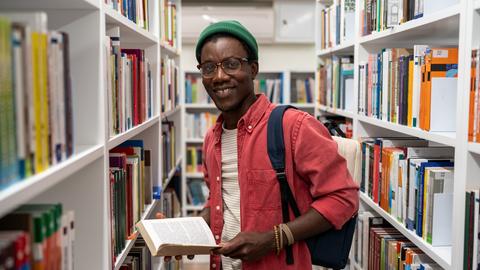 Afroamerikaner schmökert in einer Bibliothek
