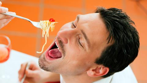 Ein Mann isst Spaghetti.