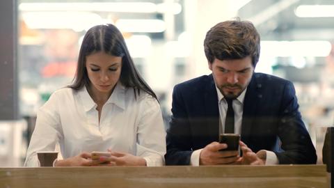 Eine Frau und ein Mann beschäftigen sich mit ihren Smartphones.