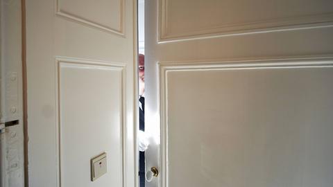Mann blickt durch einen Türspalt