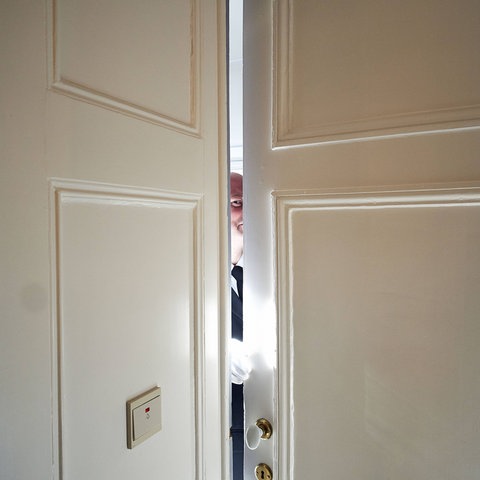 Mann blickt durch einen Türspalt