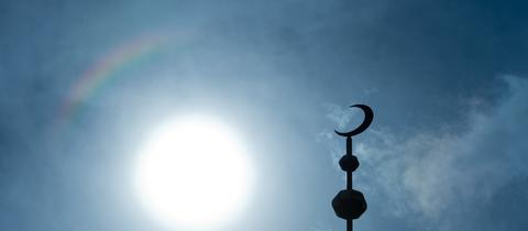 Der Halbmond auf dem Minarett der Abubakr Moschee hebt sich als Schattenriss vor der Sonne ab