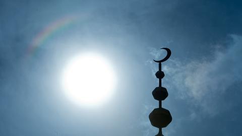 Der Halbmond auf dem Minarett der Abubakr Moschee hebt sich als Schattenriss vor der Sonne ab