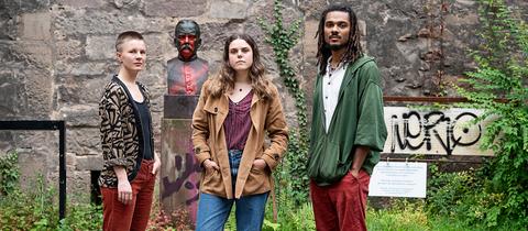Drei junge Leute vor einer Bronze-Statue von Kolonialschul-gründer Fabarius