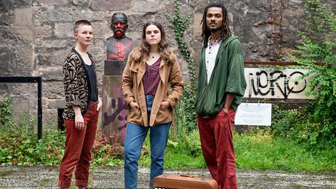 Drei junge Leute vor einer Bronze-Statue von Kolonialschul-gründer Fabarius