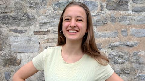 Junge Frau mit langen Haaren vor einer Backsteinmauer