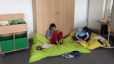 Schüler lesen auf dem Boden sitzend