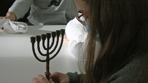 Ein Mädchen untersucht einen siebenarmigen Leuchter  im Jüdischen Museum Frankfurt.