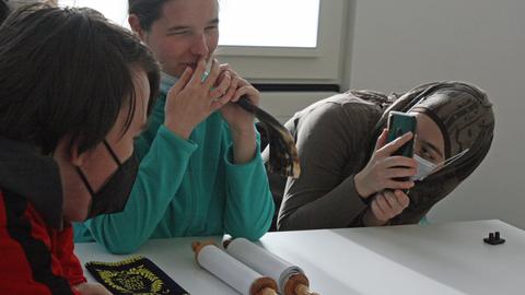 Eine Schülerin pustet in ein Horn, eine andere filmt sie mit dem Smartphone.