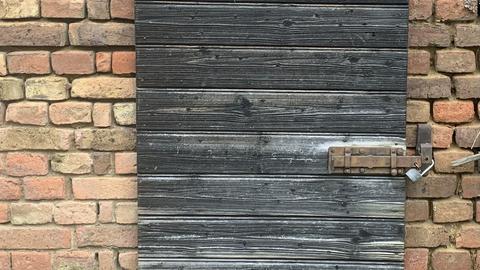Verwitterte Holztür in einer Backstein-Wand