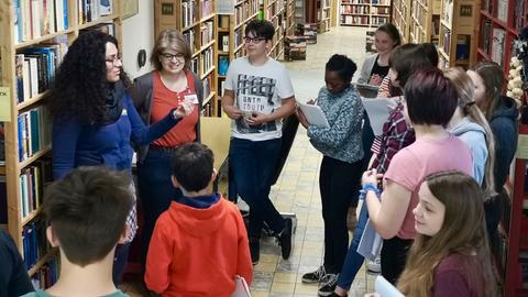 Safiye Can mit Schülern zwischen den Bücherregalen in der phantastischen Bibliothek