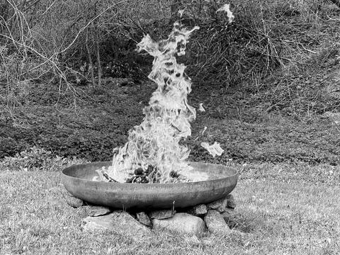 Impressionen aus dem Vogelsberg: eine auf Steinen gelagerte Feuerschale, aus der sich eine große Flamme erhebt und sich in die Luft verflüchtigt