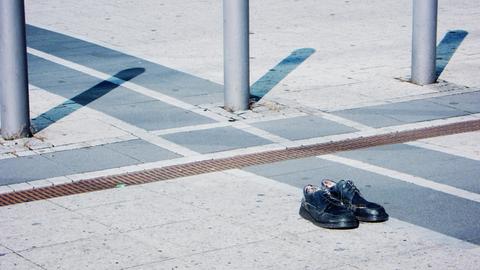 Öffentlicher Raum: ein Paar schwarzer Schuhe stehen adrett beieinander auf Plattenbelag eines Platzes