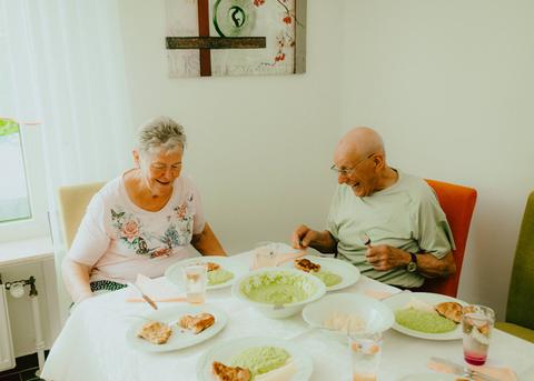 Reportage-Foto: Ein heiteres älteres Ehepaar sitzen bei Grüner Sosse und Schnitzel am Tisch