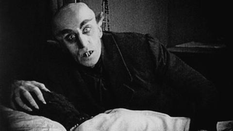Filmbild aus Nosferatu - ein Vampir kniet vor einer Frau