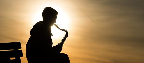Ein Mann spielt auf dem Tempelhofer Feld in Berlin auf seinem Saxofon.