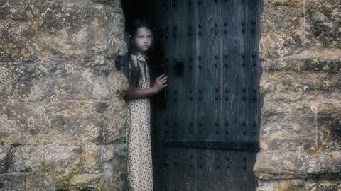 ein Mädchen schaut aus einer Tür