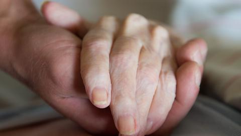 Ein Pfleger hält eine Hand.