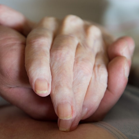 Ein Pfleger hält eine Hand.
